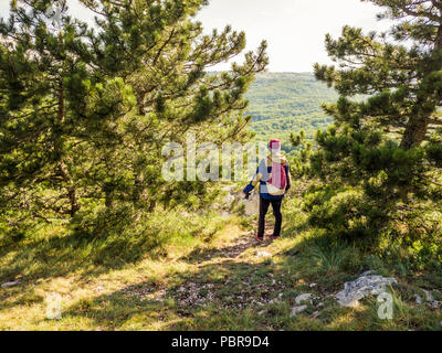portrait of young man photographer in the mountain forest looking on landscape panorama and make photo with camera Stock Photo