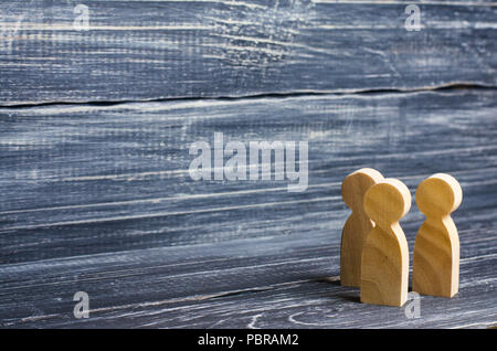 Three wooden human figures stand together. Social concept, family, team, friends, brothers and sisters. Space for text. Stock Photo