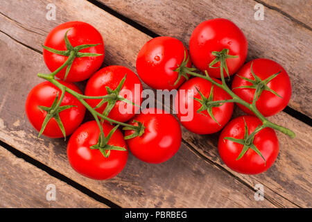 Two branches with ripe delicious tomatoes. Rustic wooden background. Top view. Stock Photo