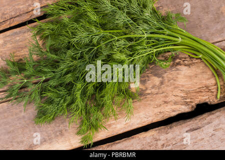 Fresh ripe green dill on wood. Top view. Old rustic wooden desk table background. Stock Photo