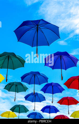 Colourful umbrellas floating in a blue sky Stock Photo