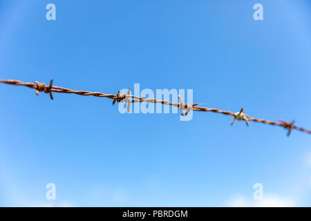 Rusty barbed wire against blue sky Stock Photo