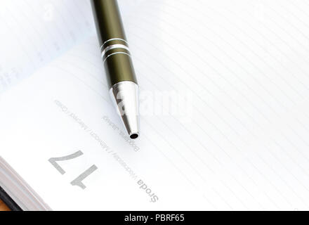 Closeup of pen lying on open organizer or calendar on desk in office Stock Photo