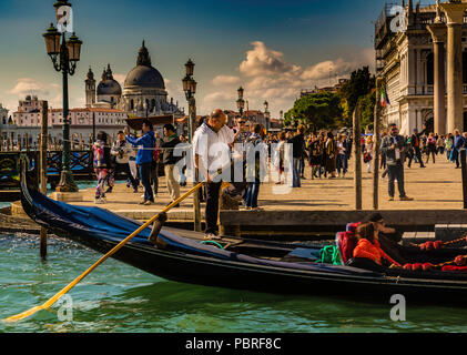 A Venice gondolier shoves off his gondola with a full load of tourists Stock Photo