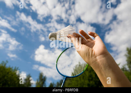 A female hand holds a shuttlecock against the sky. Sport. Stock Photo