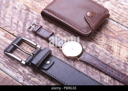 Set of men's accessories for the business with leather belt, wallet, watch and smoking pipe on a wooden background. The concept of fashion and travel. Stock Photo