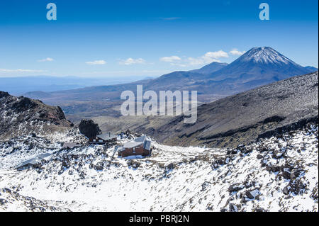 View from Mount Ruapehu on Mount Ngauruhoe with a ski cottage in the foreground, Unesco world heritage sight Tongariro National Stock Photo