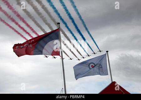 Framed by flags the Red Arrows make a flypast at Scotland's national airshow held at the national museum of flight, East Fortune near Edinburgh Stock Photo