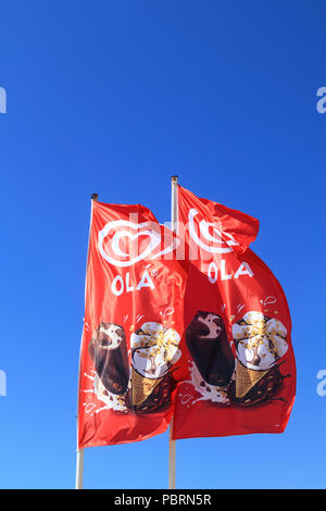 Bright red flags flying the brand Ola ice cream against a clear blue sky with space for copy Stock Photo