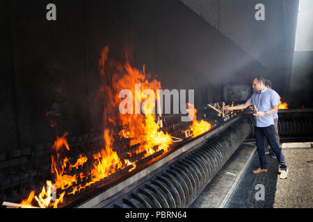 Two men place  votive candles to burn in the pyre as fulfillment of vows made to Our Lady Fatima Portugal Stock Photo