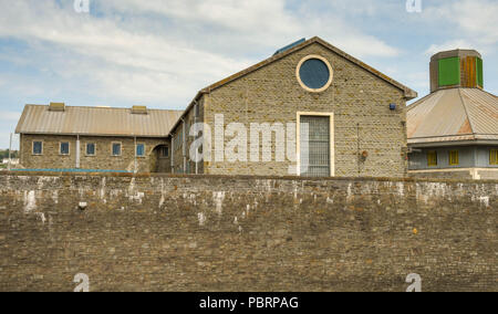 Wide angle view of buildings and the external high wall of HM Prison Swansea Stock Photo