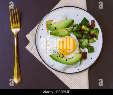 A healthy breakfast of toast with avocado, whole wheat bread and fried egg and burrito salad on white plate Stock Photo
