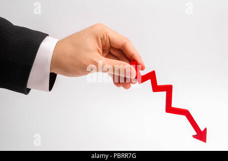 A businessman's hand is holding a red arrow down on a white background. The concept of reducing costs and profits, falling living standards and prices Stock Photo