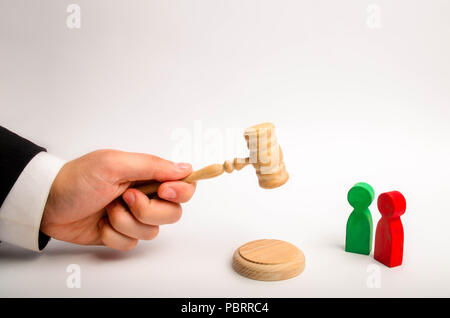 The referee's hand holds a hammer and issues a verdict in the dispute between the red and green opponents. court cases, the resolution of disputes and Stock Photo