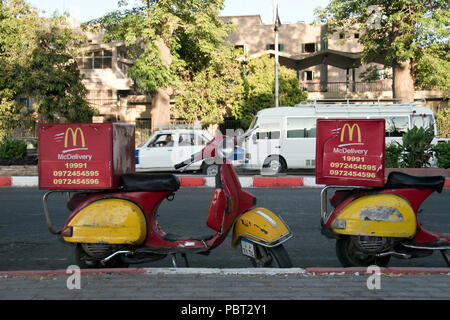 Scooters for home delivery parked outside the McDonald’s fast food restaurant on the Nile at Aswan, Egypt. Stock Photo