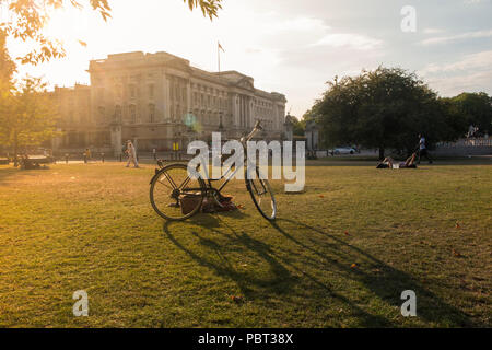 A lady snoozes by her bike outside Buckingham Palace on parched grass of a hot summer Stock Photo