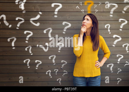 Question Marks with young woman in a thoughtful pose Stock Photo