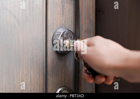 Woman's hand puts the key in the keyhole of wooden door. Home security concept Stock Photo