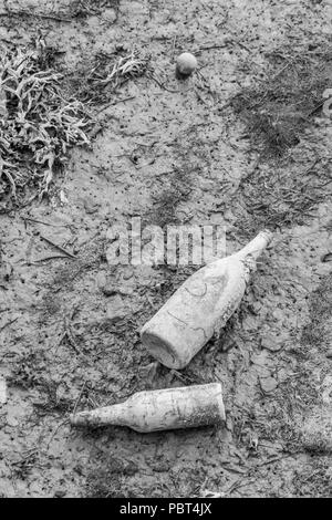 Black and white rendition of PBT4JN - Two old glass bottles in the muddy flats of an estuarine river after the tide has gone down. Stock Photo