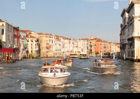 Water taxis with tour groups on the Grand Canal at sunset, Venice, Veneto, Italy passing the historic palazzos, palaces of Cannaregio. Busy water traf Stock Photo