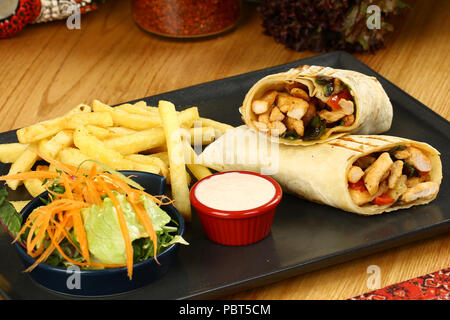 Fried chicken stuffed tortilla wrap sandwich with vegetables and french fries Stock Photo