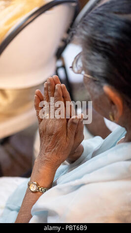 A close up photo of an older Hindu woman's hands clasped together during prayer and meditation. In South Ozone Park, Queens, New York.