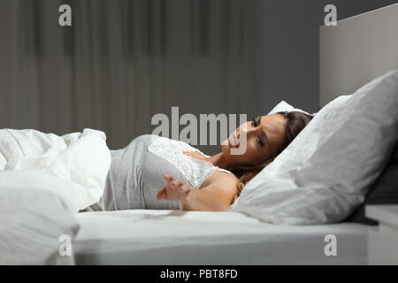 Sad single woman missing her husband in the night on a bed at home Stock Photo