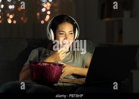 Single woman watching online tv in the night sitting on a couch in the living room at home Stock Photo