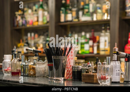 Professional cocktail tools and ingredients in glass bottles and jars for creative modern fashionable cocktails on wooden bar counter. Stock Photo