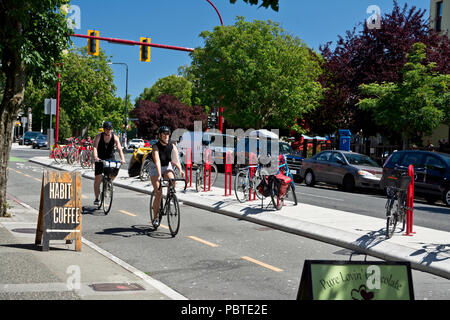 Cyclists riding in bike lanes in downtown Victoria, British Columbia, Canada. Summer bike riding in Victoria BC Canada Stock Photo