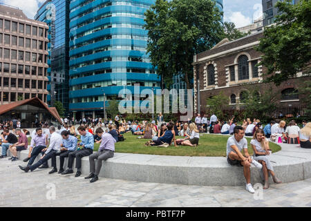 Local office workers and tourists enjoying a sunny Lunchtime break in Aldgate Square. St Botolph Building, church and Portsoken Pavilion.London, UK Stock Photo