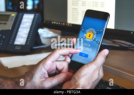 Man holding a mobile smart phone with a data security application displaying a yellow padlock and pressing OK button with finger Stock Photo