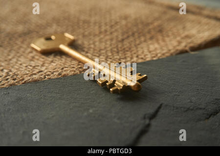 Conceptual close-up of a vintage golden key as symbol for acces, property or security. Selective focus and free copy space. Stock Photo