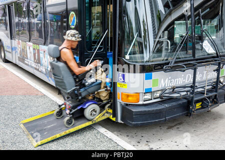 Miami Florida,bus mass transit adult man passenger rider,electric wheelchair,physically handicapped disabled disability accessible boarding ramp Stock Photo