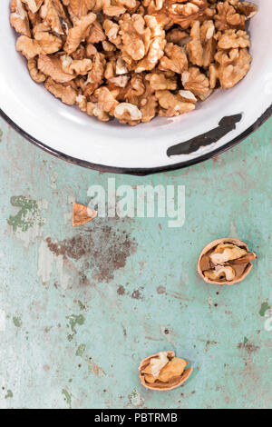 Walnuts on old plateau over a green wooden table. Stock Photo
