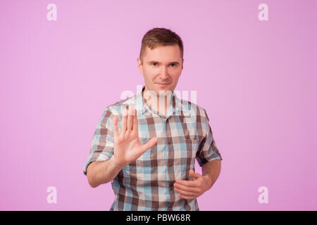 Portrait of european serious young man stretching hand towards camera with stop or hold gesture Stock Photo