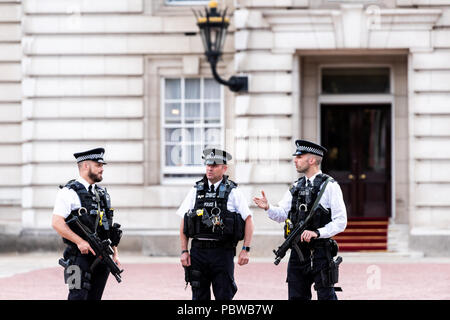 London, UK - June 21, 2018: Three English Royal security guards police officers with automatic weapons guns standing talking in front of Buckingham Pa Stock Photo