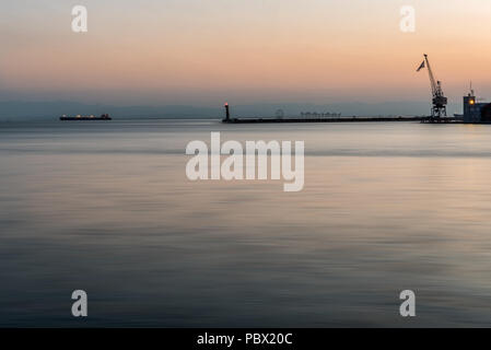 Thessaloniki Pier and Lighthouse at peaceful sunset, with a single ship in the background, Greece Stock Photo