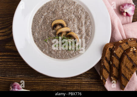 Cream of mushroom soup with ray bread toasts on wooden table, top view Stock Photo