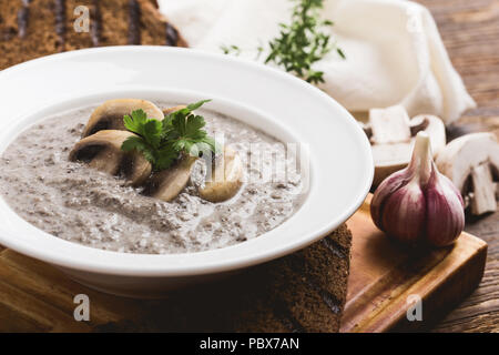 Cream of mushroom soup with ray bread toasts on wooden table Stock Photo