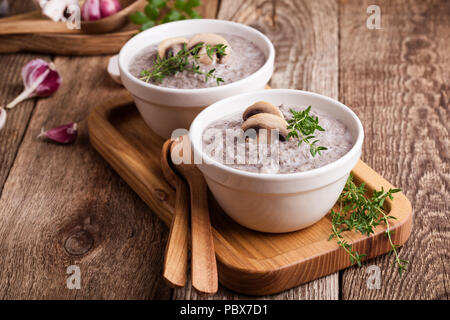 Hearty mushroom soup in ceramic bowl on wooden table Stock Photo