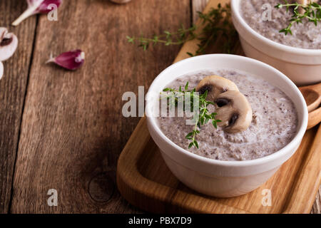 Hearty mushroom soup in ceramic bowl on wooden table Stock Photo