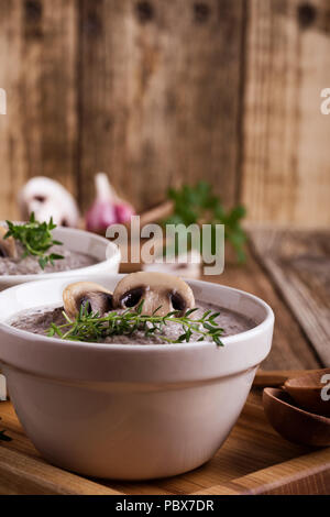 Hearty mushroom soup in ceramic bowl on wooden table Stock Photo