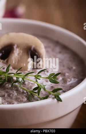 Hearty mushroom soup in ceramic bowl on wooden table Stock Photo