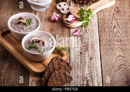 Hearty mushroom soup in ceramic bowl on wooden table Stock Photo