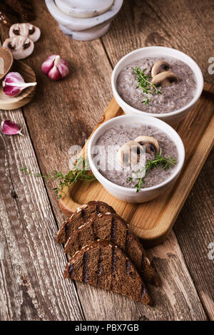 Hearty mushroom soup in ceramic bowl on wooden table Stock Photo