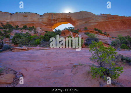 Sun setting behind an arch at Arches National Park Stock Photo