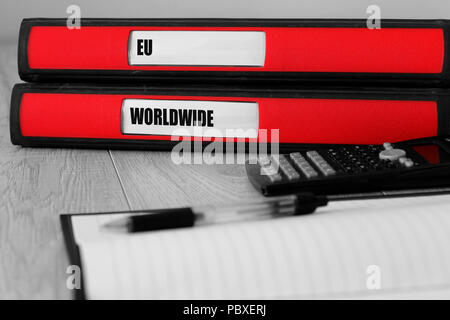 Red folders with eu and worldwide written on the label on a desk with selective colour Stock Photo