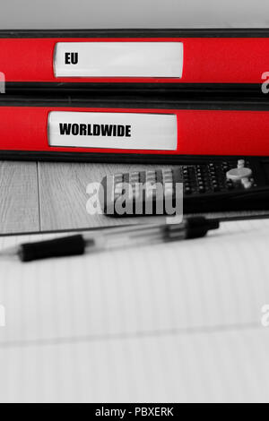 Red folders with eu and worldwide written on the label on a desk with selective colour Stock Photo