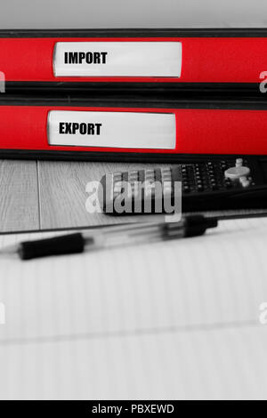 Red folders with import and export written on the label on a desk with selective colour Stock Photo